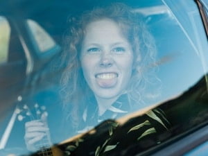 Jeune fille tire la langue derriere vitre de voiture réparée